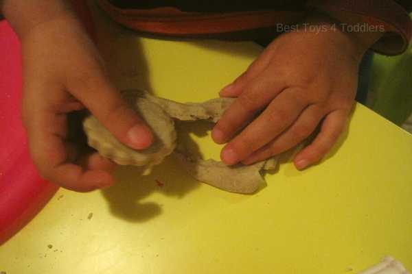toddler is practicing fine motor skills with homemade playdough